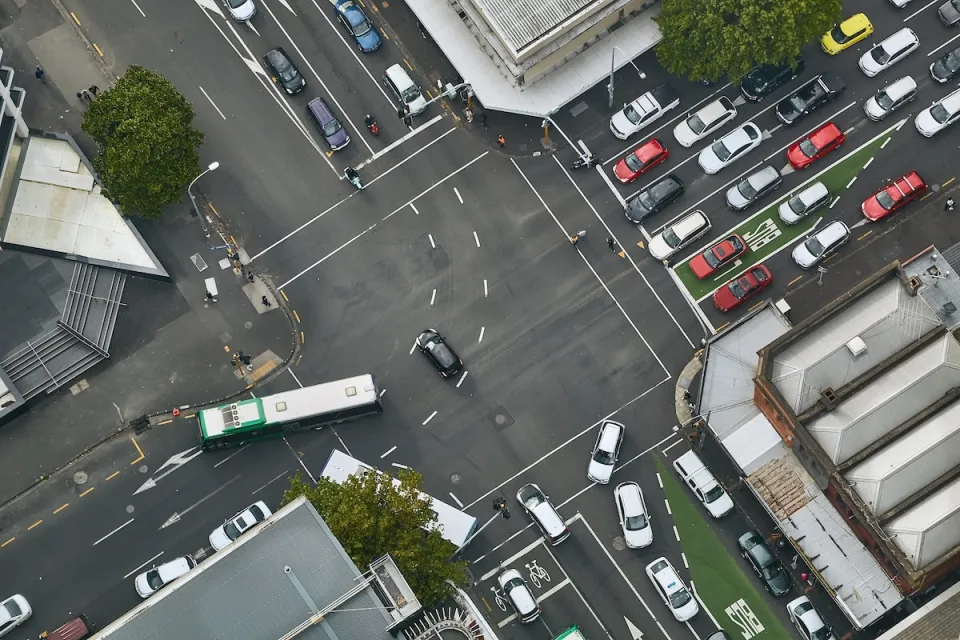 Bird's eye view of busy urban intersection with bus lanes, traffic, and pedestrians.